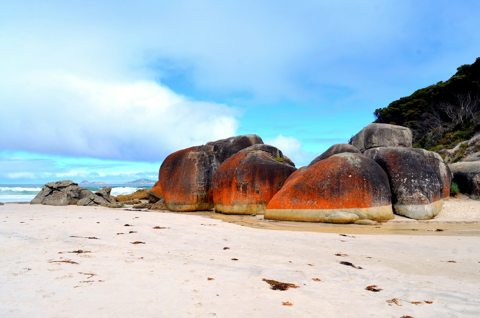 Rounded granite boulders with orange markings on a pale beach at Wilsons Promontory.