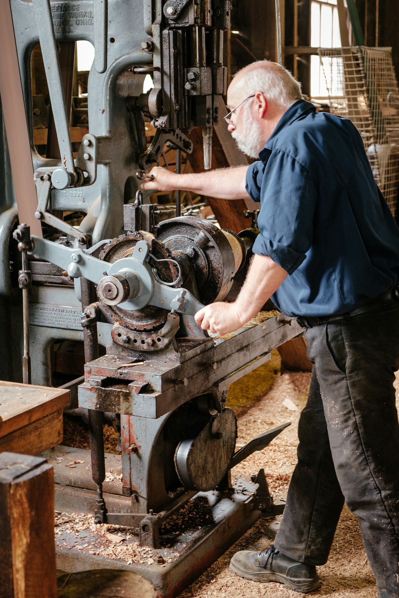 A craftsperson working at a large woodworking machine surrounded by shavings at Sovereign Hill.