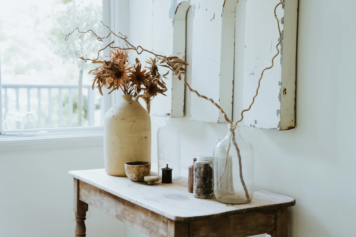Pale vessels and dried stems against a light interior wall.