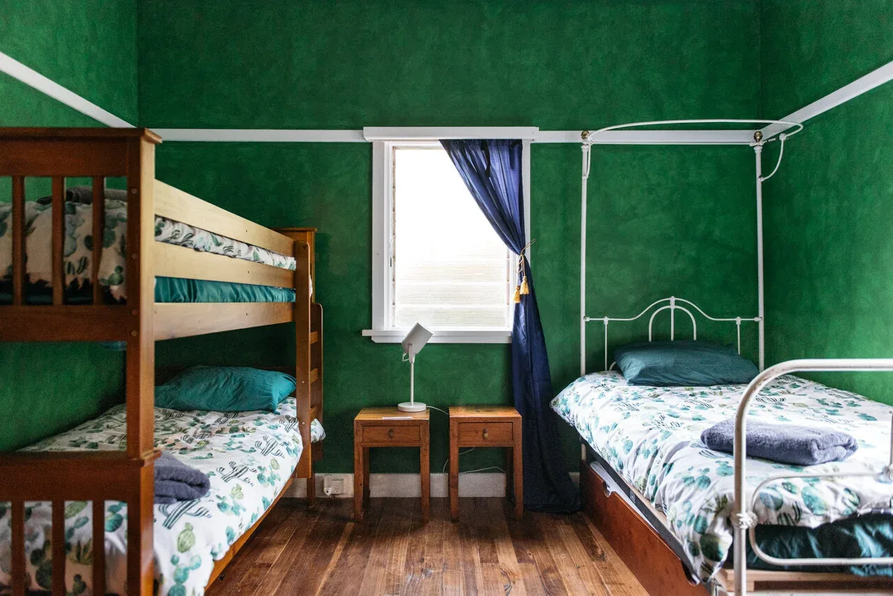 Green bedroom walls and pale metal bed frames.